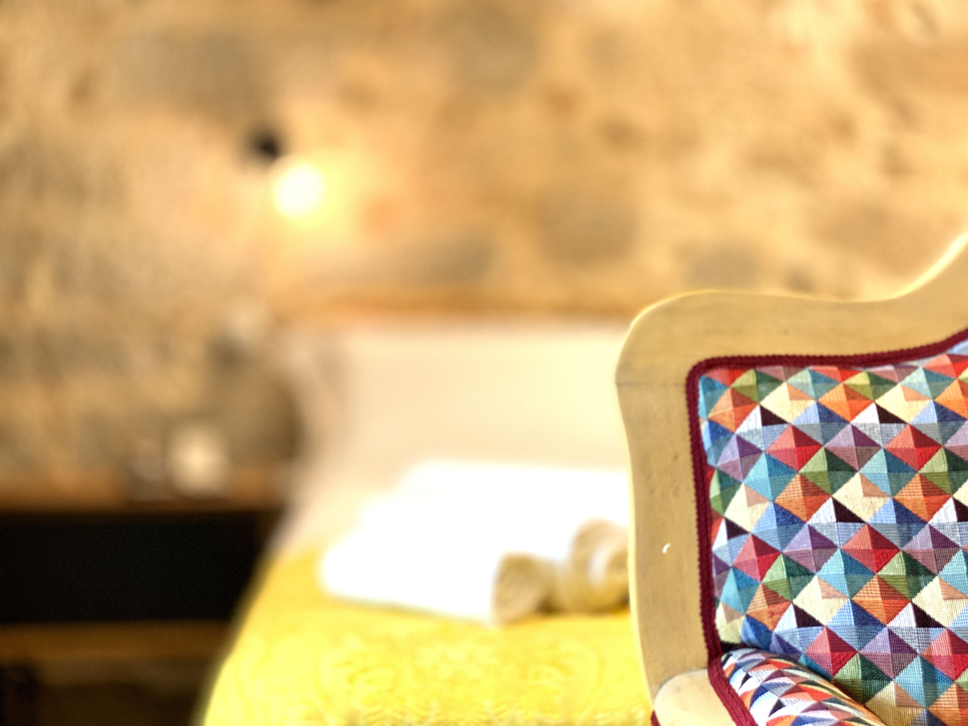 A close-up of a chair with a colorful geometric-patterned cushion.
