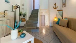 A living room with a sofa, a coffee table, a staircase, and a dining area with a table and chairs. - Villa marta, just 100 m from Cala Caterina (villasimius)