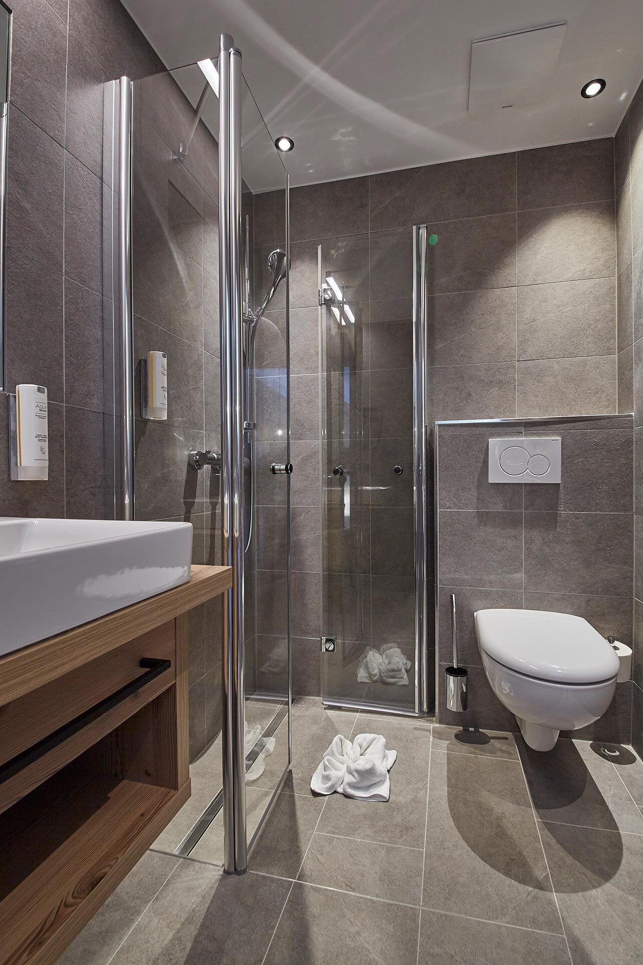 Ein modernes Badezimmer mit einer Glasdusche, einem weißen Waschbecken und einer Toilette.