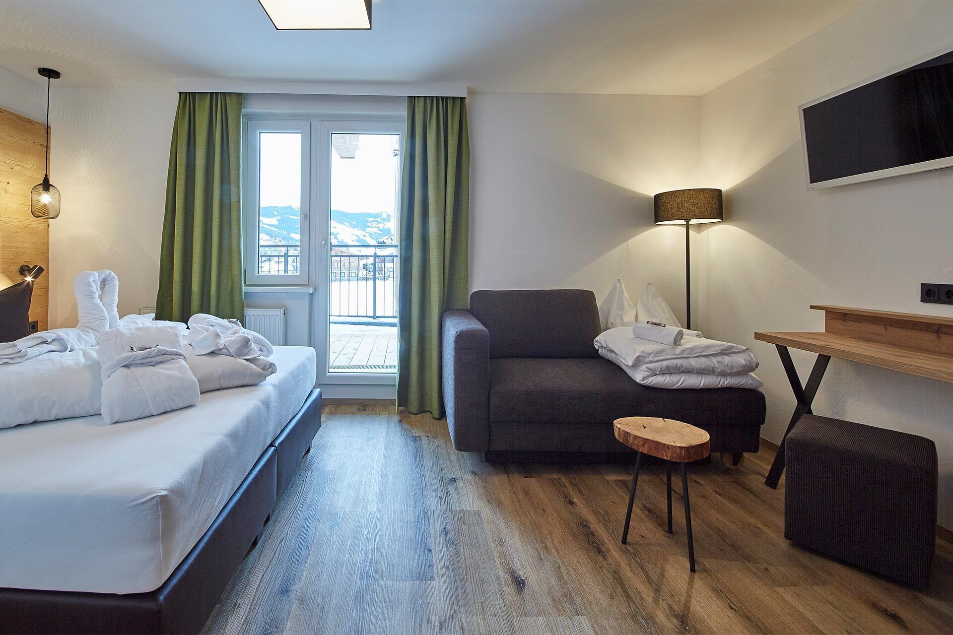 Ein Hotelzimmer mit Bett, einer Couch, einem kleinen Tisch und einer Lampe.