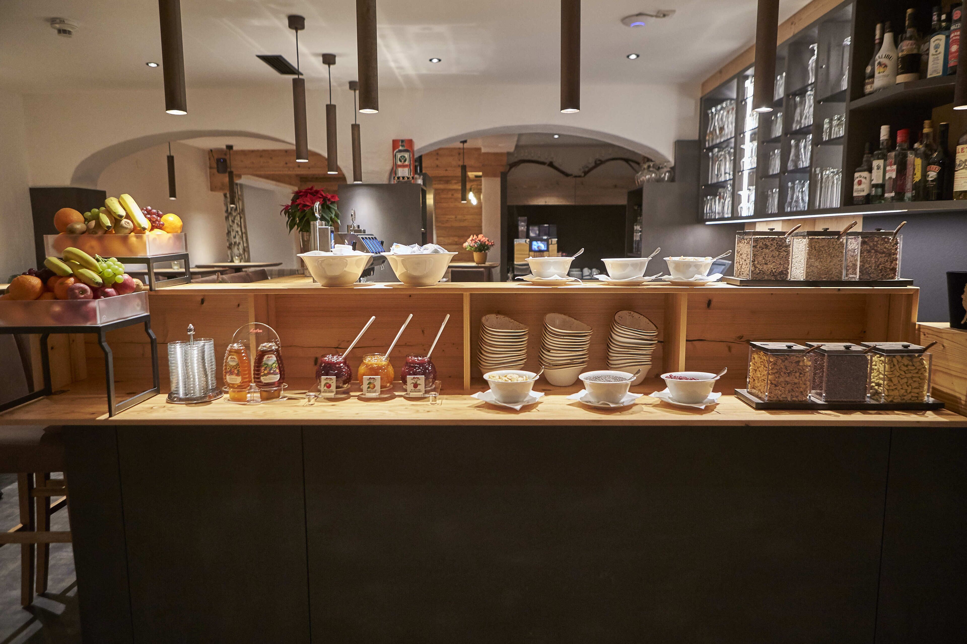 Uma área de bar com balcão de madeira, diversos alimentos e uma seleção de bebidas.
