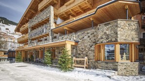 A multi-story hotel with a stone facade and wooden balconies. - Hotel Hubertushof (Saalbach-Hinterglemm)