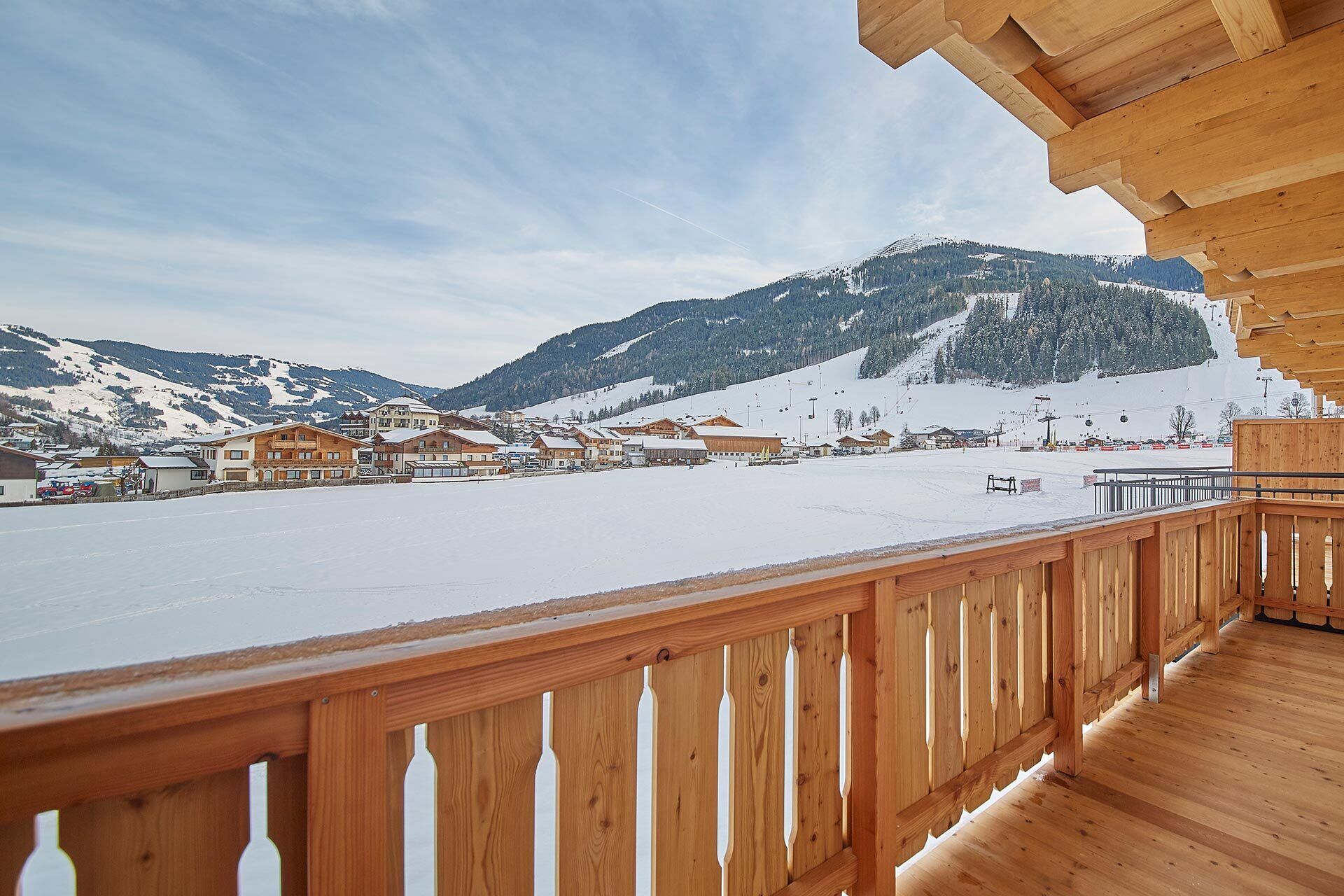 A wooden deck with a view of a snow-covered landscape and buildings.