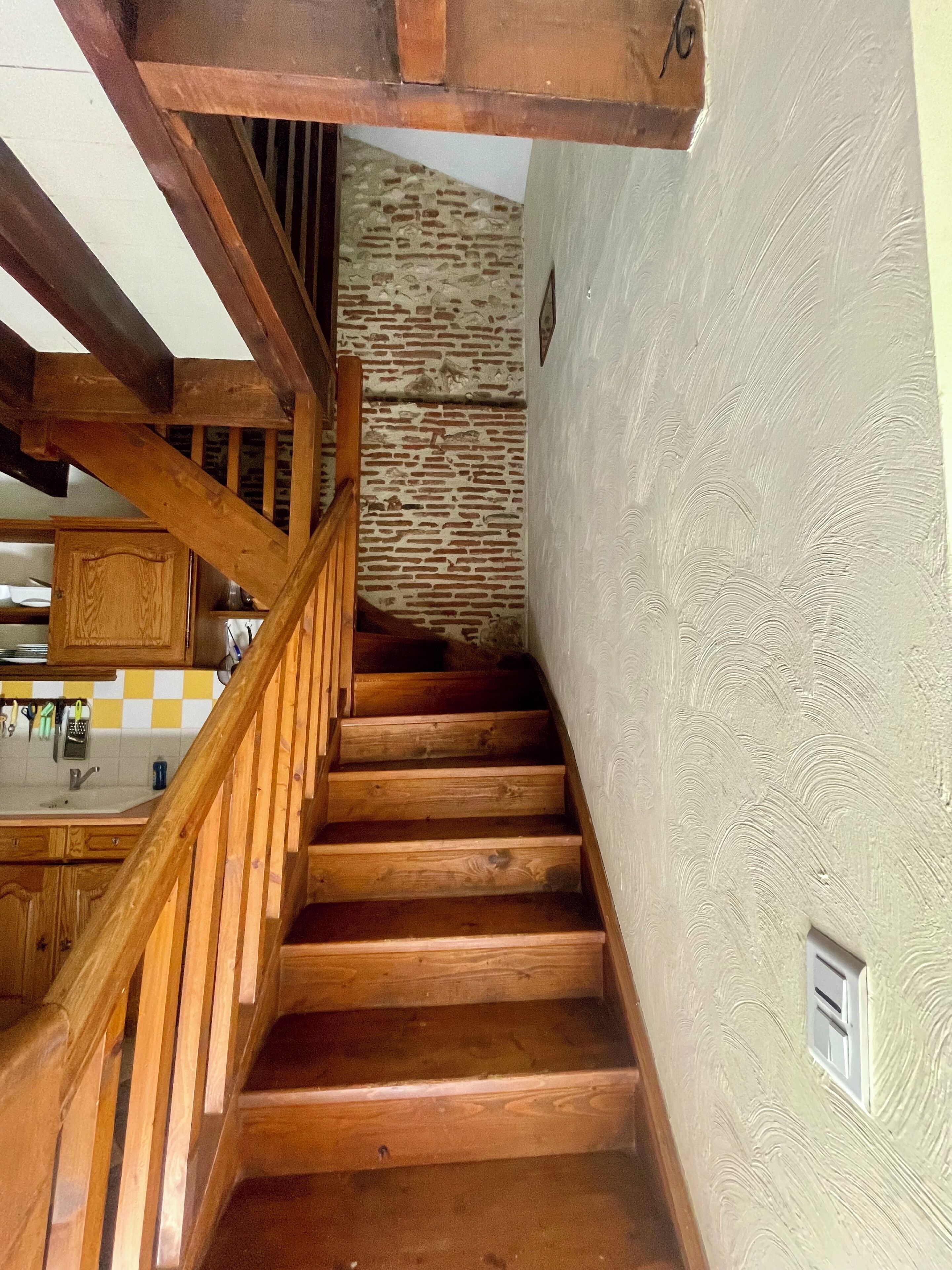 A wooden staircase with a stone wall in the background.