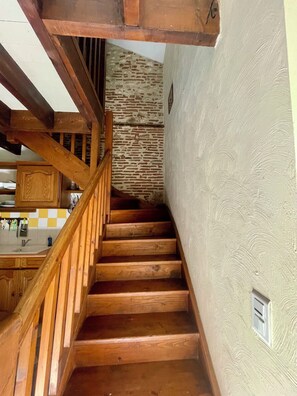 A wooden staircase with a stone wall in the background.