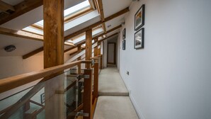 Eine hölzerne Treppe mit Glasgeländern, die zu einer Zwischenebene führt.