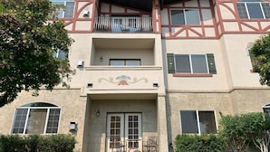 A multi-story building with a symmetrical facade, a central entrance with a decorative arch, and a balcony on the upper floor.
