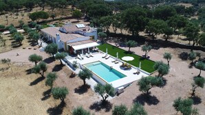 A large house with a swimming pool, outdoor seating, and a well-maintained lawn.