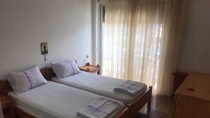 Una habitación con dos camas individuales, una mesita de noche de madera, una pequeña mesa y un radiador.