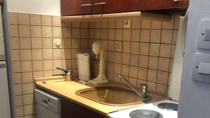 Una cocina compacta con lavavajillas, un fregadero y una estufa.