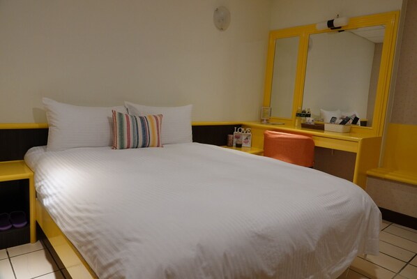 Relax in a spacious room with a large bed, a desk, and a comfortable chair.