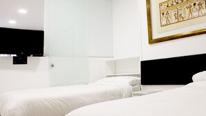A hotel room with two beds, a flat-screen TV mounted on the wall, and a framed picture above the beds. - Apartamentos Funway Hostel (Madrid)