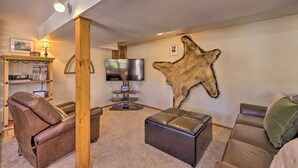Ein Wohnzimmer mit Ledersofa, Ottoman und einem an der Wand aufgehängten Tierfell.