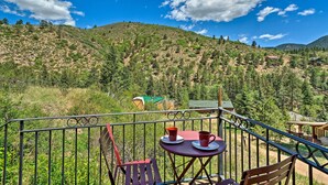 Ein Balkon mit Tisch und Stühlen mit Blick auf eine gebirgige Landschaft.
