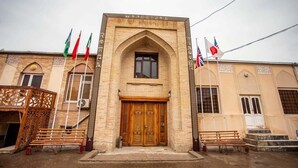 A building with a central arched entrance, flanked by two wings with windows and doors. - Reikartz Modarixon Bukhara (Bukhara)