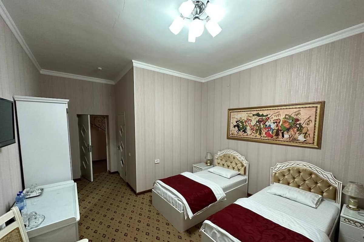 A hotel room with two beds, a desk, a chair, a television, and a painting on the wall.