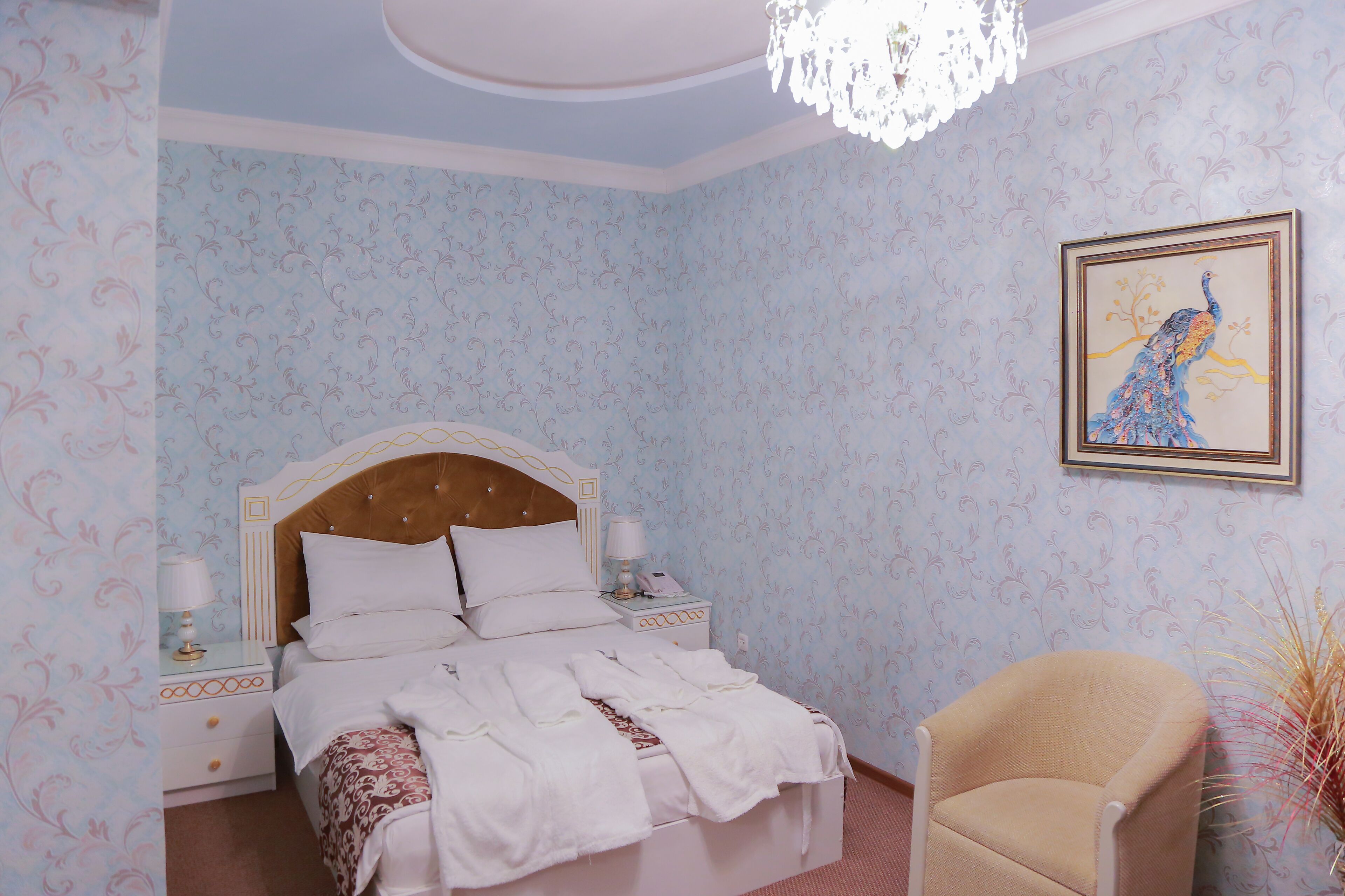 A bedroom with a bed, bedside tables, a chair, and a wall painting.
