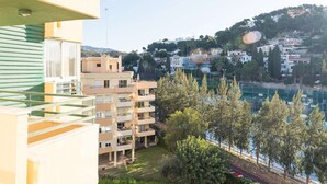 A multi-story building with balconies, a view of a hillside with houses, and a body of water in the background. - Beautiful Studio Near the Beach (Malaga)