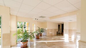 A spacious hallway with a marble floor, potted plants, and a view of the outdoors through large windows. - Beautiful Studio Near the Beach (Malaga)