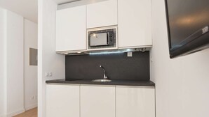 A compact kitchen with white cabinets, a black countertop, and a stainless steel sink. - Beautiful Studio Near the Beach (Malaga)