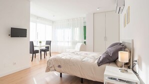 Une chambre à coucher comprenant un lit, une table de chevet, une lampe et un téléviseur fixé au mur.