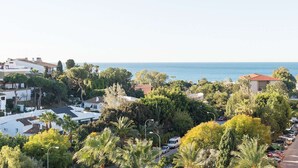 Un quartier résidentiel situé sur la côte, avec des maisons, des voitures garées et une végétation luxuriante.