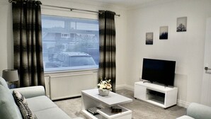 Una sala de estar moderna con sofá, mesa de centro y mueble para televisor.