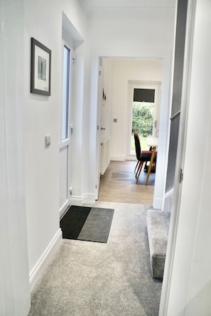 Enter a serene space leading to a dining area with a view of lush greenery.