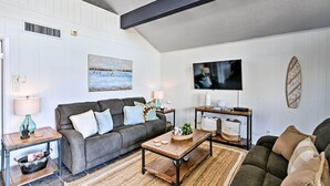 Een woonkamer met een grijze bank, een houten salontafel en een televisie op een meubel.