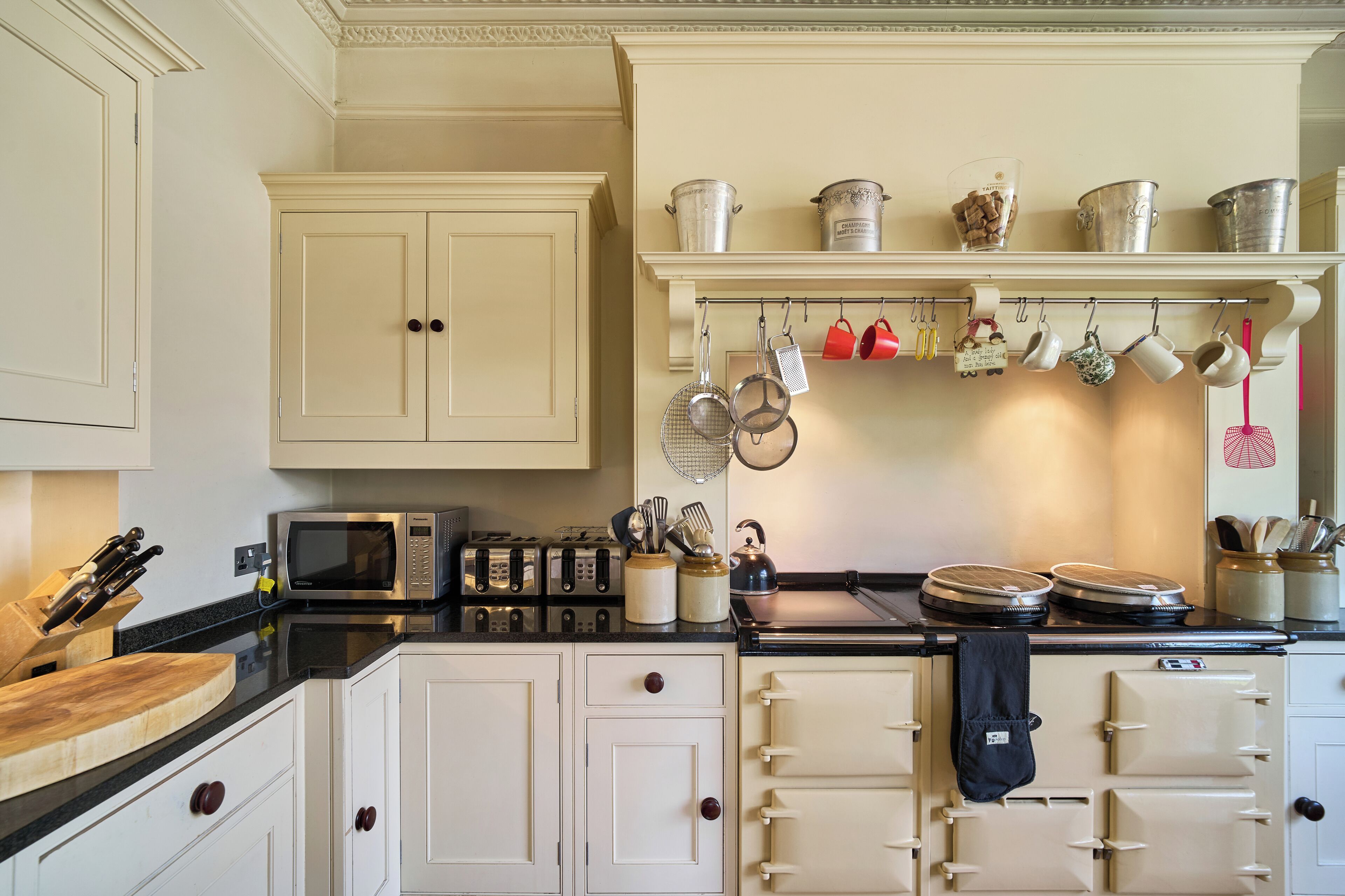 A kitchen with white cabinets, a microwave, a toaster, and hanging utensils.