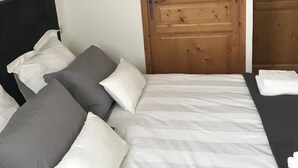 Ein Schlafzimmer mit einem Bett, Kissen, einem Holzschrank und einer Tür.