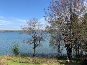 Blick auf einen See mit Bäumen und blauem Himmel.