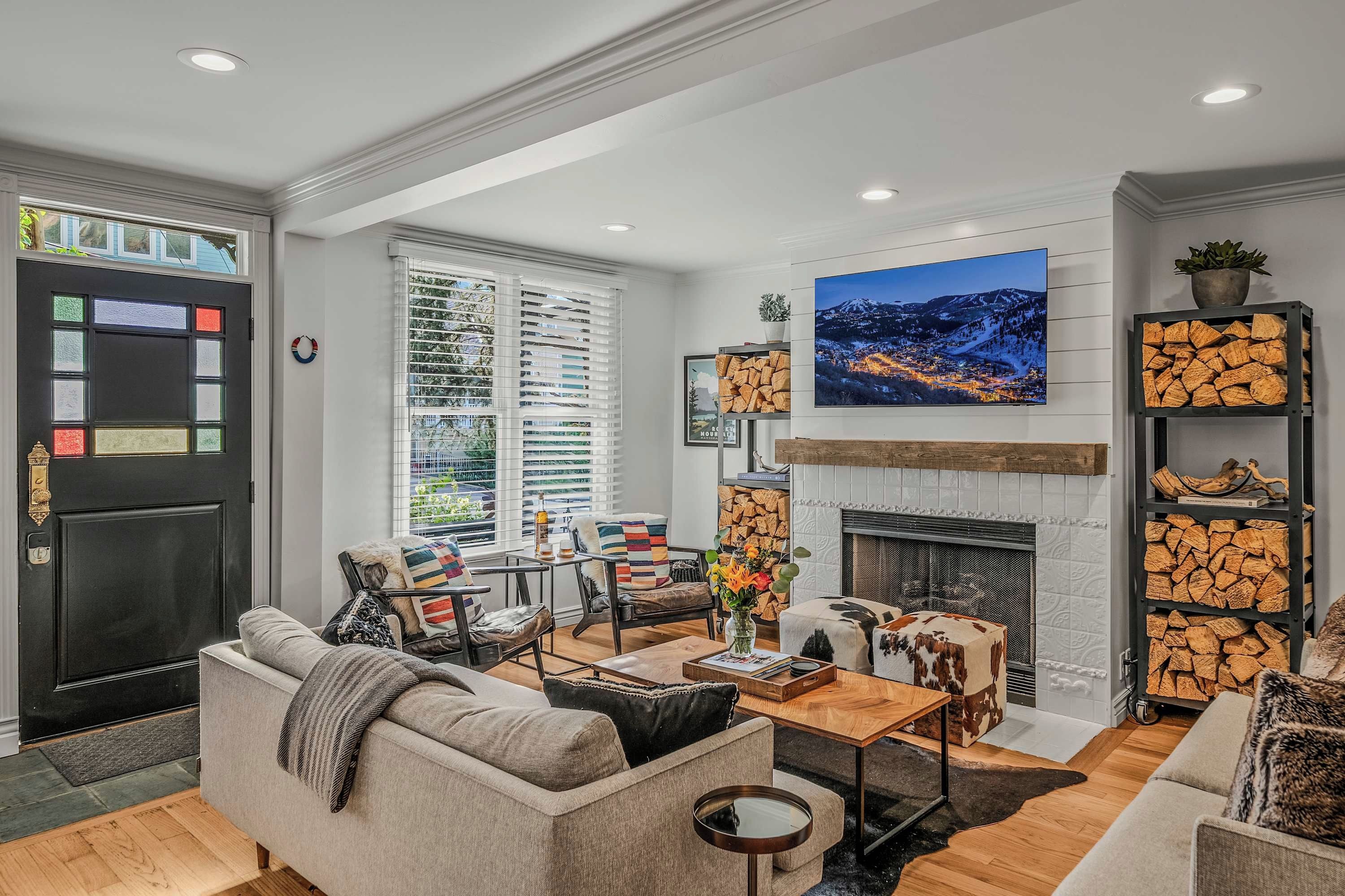 A modern living room with a fireplace, seating area, and a large window.