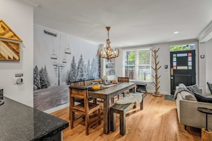A modern kitchen with a dining area, wooden flooring, and a decorative wall mural. - Abode at Watson House, private hot tub, walk to town lift & Main Street (Park City)