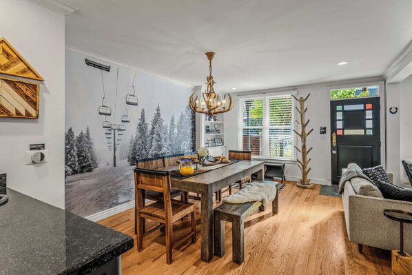 A modern kitchen with a dining area, wooden flooring, and a decorative wall mural.