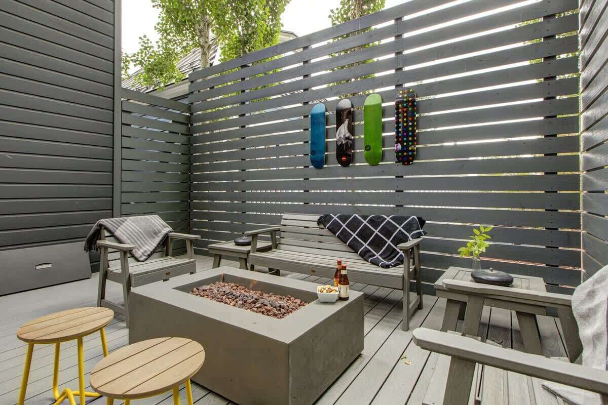 An outdoor patio with a fire pit, seating, and a wall-mounted skateboard rack.