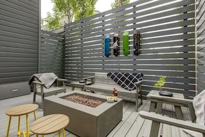 An outdoor patio with a fire pit, seating, and a wall-mounted skateboard rack.