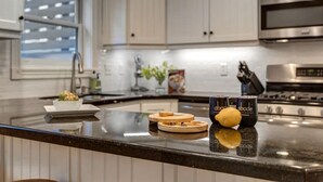 Een keuken met een zwart aanrecht, roestvrijstalen apparatuur en een raam met jaloezieën.
