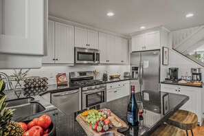 Een moderne keuken met witte kasten, roestvrijstalen apparatuur en een centraal eiland met een fruitschaal.