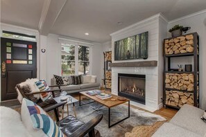 Una sala de estar con chimenea, un sofá, una mesa de centro y una estantería.