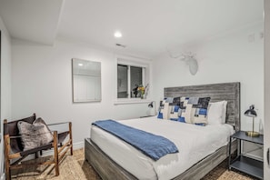 A bedroom with a bed, a chair, a nightstand, a lamp, a window with a view, and a wall-mounted mirror. - Abode at Watson House, private hot tub, walk to town lift & Main Street (Park City)