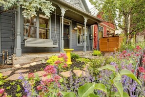 Una casa con porche, una hamaca y un jardín con diversas plantas y flores.