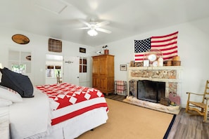 A bedroom with a bed, a fireplace, an American flag, and a door with a number.