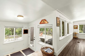 A bright, spacious room with large windows, a wooden floor, and a door leading to an outdoor deck.
