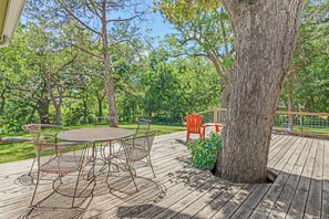A wooden deck with a table and chairs, surrounded by trees.