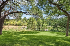 A grassy field with trees and a small building in the distance.