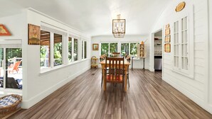 Una habitación amplia con una mesa y sillas de madera, ventanas grandes y vistas al exterior.