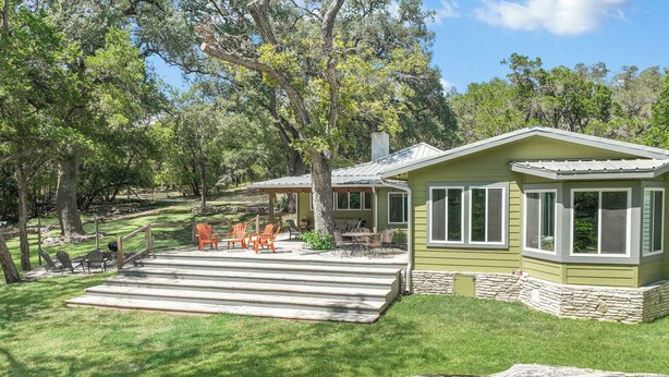 Una casa con patio, mobiliario exterior y cimientos de piedra.