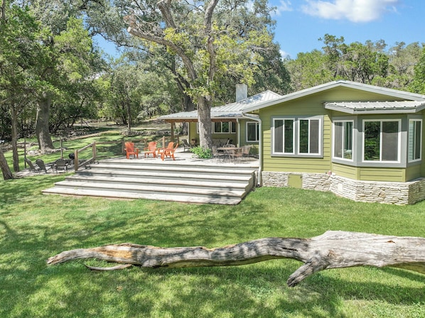 A house with a patio, outdoor seating, and a stone foundation.