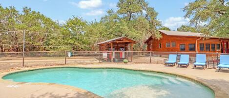 A pool area with a wooden cabin and lounge chairs.